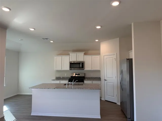 a view of kitchen with microwave stove refrigerator and cabinets