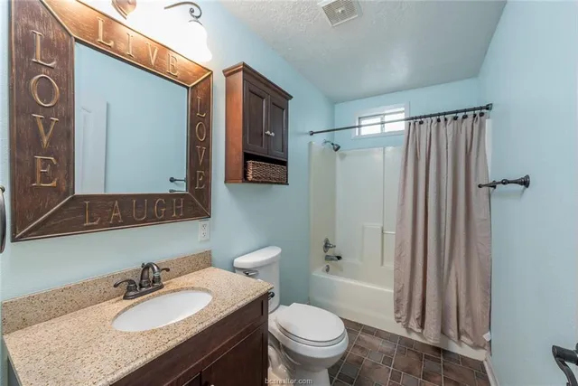 a bathroom with a granite countertop sink toilet a mirror and shower