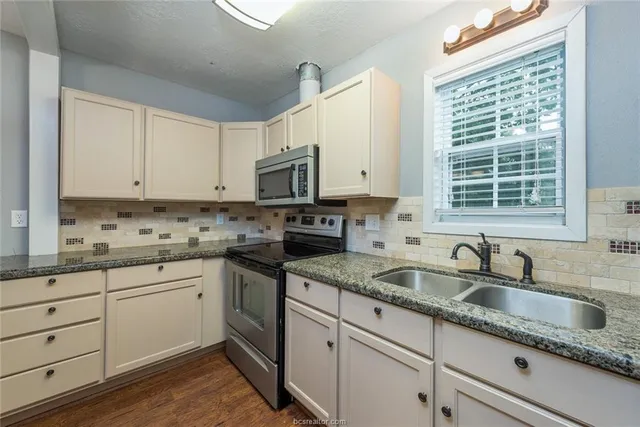 a kitchen with granite countertop white cabinets and sink