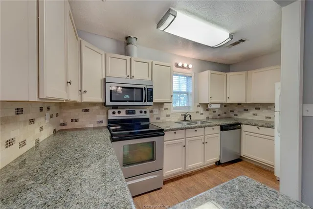 a kitchen with stainless steel appliances granite countertop a stove sink and cabinets