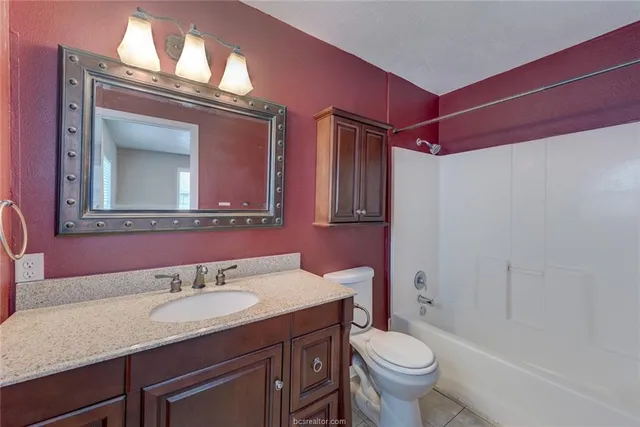 a bathroom with a granite countertop toilet sink and mirror