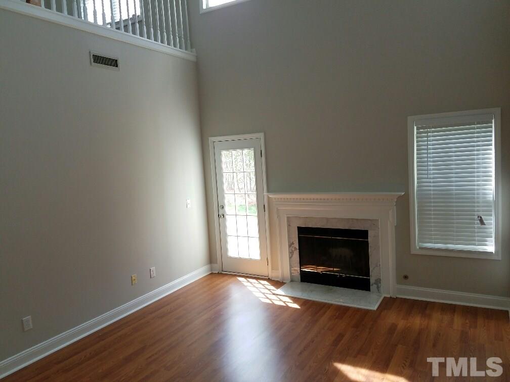 5021 Village Lawn Drive Raleigh, NC 27613 - Photo 4 of 9 an empty room with wooden floor fireplace and windows