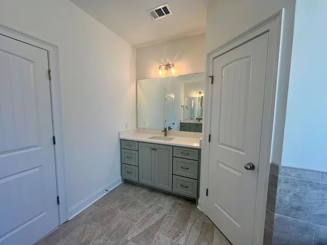 a bathroom with a vanity a sink a mirror and a shower