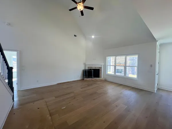 an empty room with wooden floor fireplace and windows