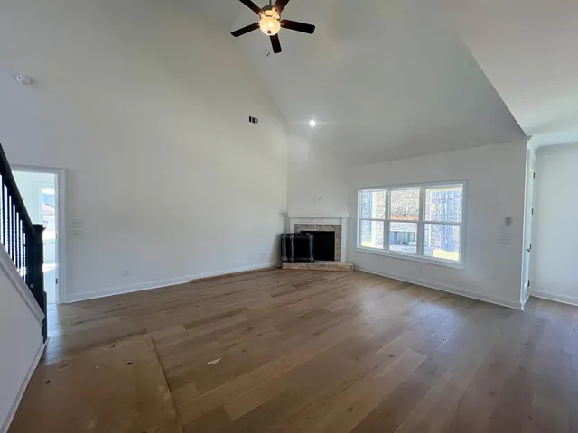 an empty room with wooden floor fireplace and windows