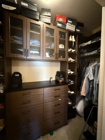 a view of walk in closet with clothes and shoes