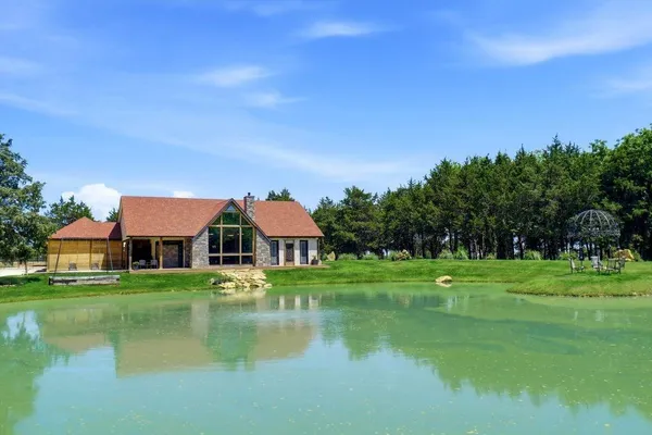 a front view of a house with a garden and lake view