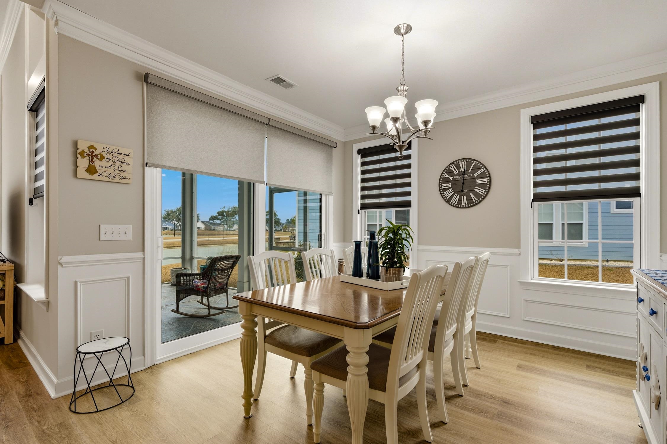 236 Bluestem Loop Little River, SC 29566 - Photo 14 of 40 Dining area with light wood-style floors, crown molding, a chandelier, wainscoting, and a decorative wall