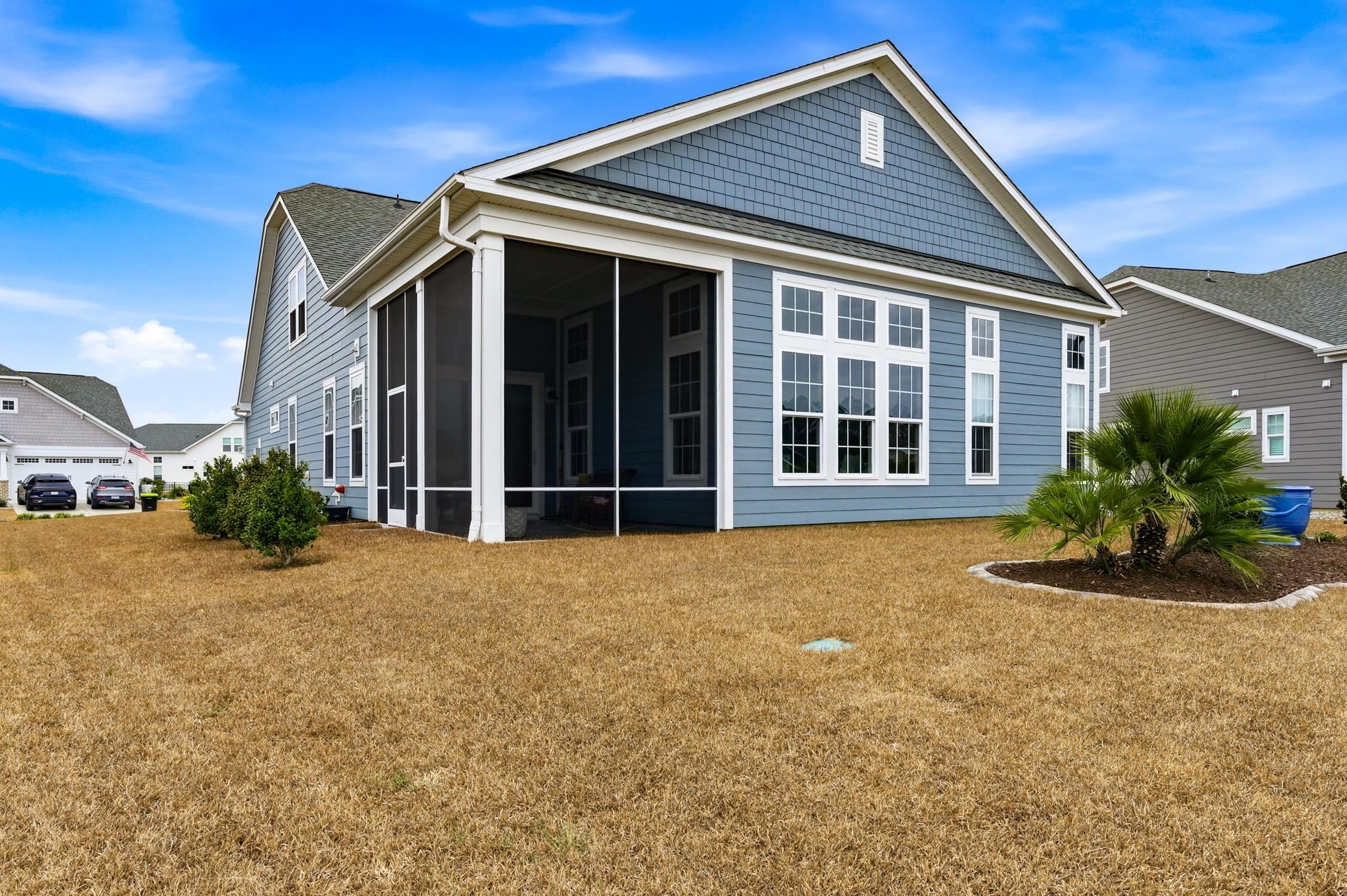 236 Bluestem Loop Little River, SC 29566 - Photo 2 of 40 Back of property featuring a sunroom, a yard, and a shingled roof