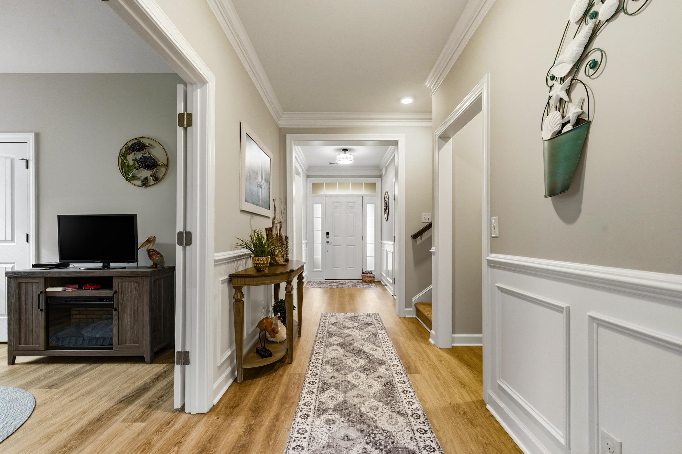 236 Bluestem Loop Little River, SC 29566 - Photo 5 of 40 Foyer with crown molding, a wainscoted wall, light wood-type flooring, a decorative wall, and stairs