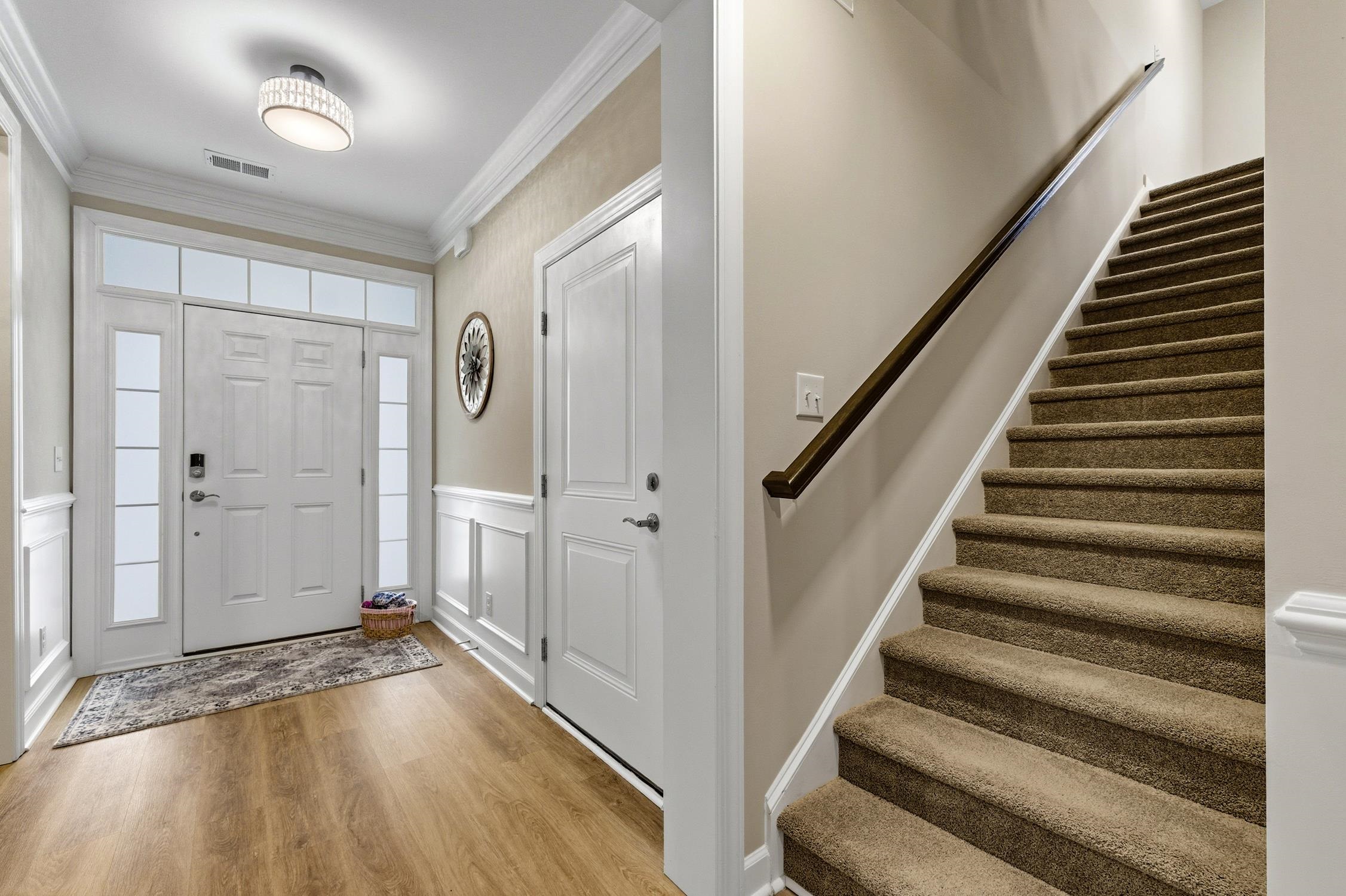 236 Bluestem Loop Little River, SC 29566 - Photo 6 of 40 Entryway featuring ornamental molding, stairway, a wainscoted wall, a decorative wall, and light wood-style flooring