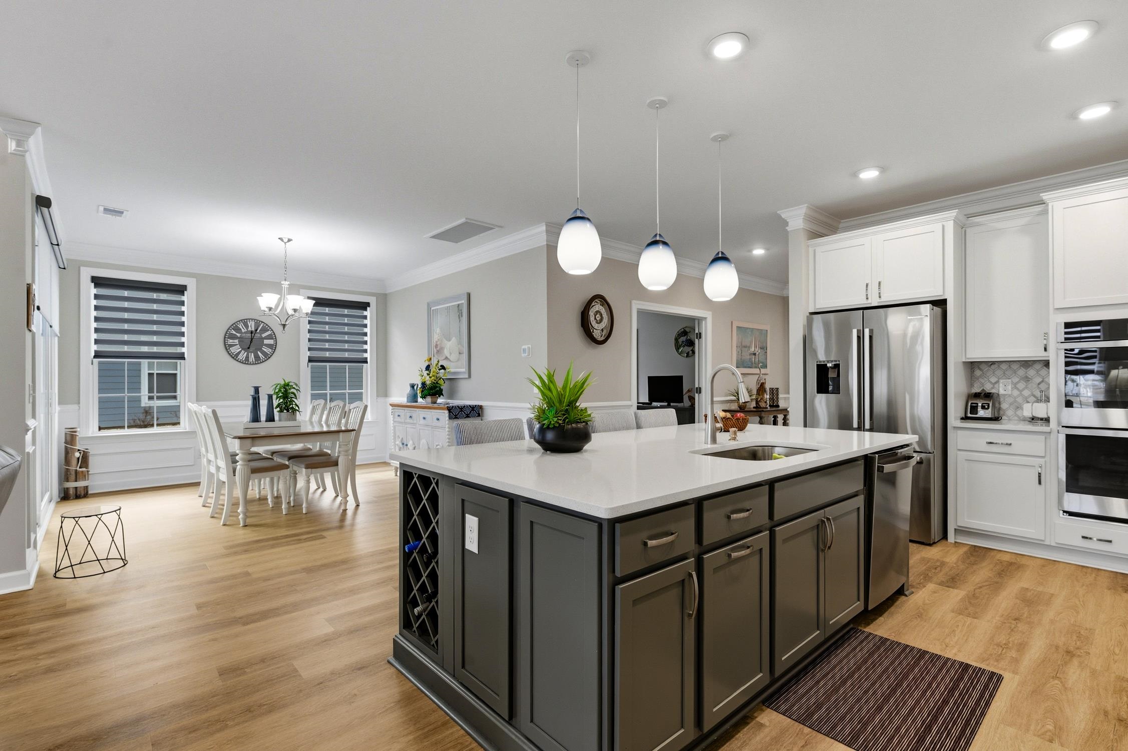 236 Bluestem Loop Little River, SC 29566 - Photo 8 of 40 Kitchen with white cabinets, pendant lighting, a kitchen island with sink, light stone counters, and crown molding
