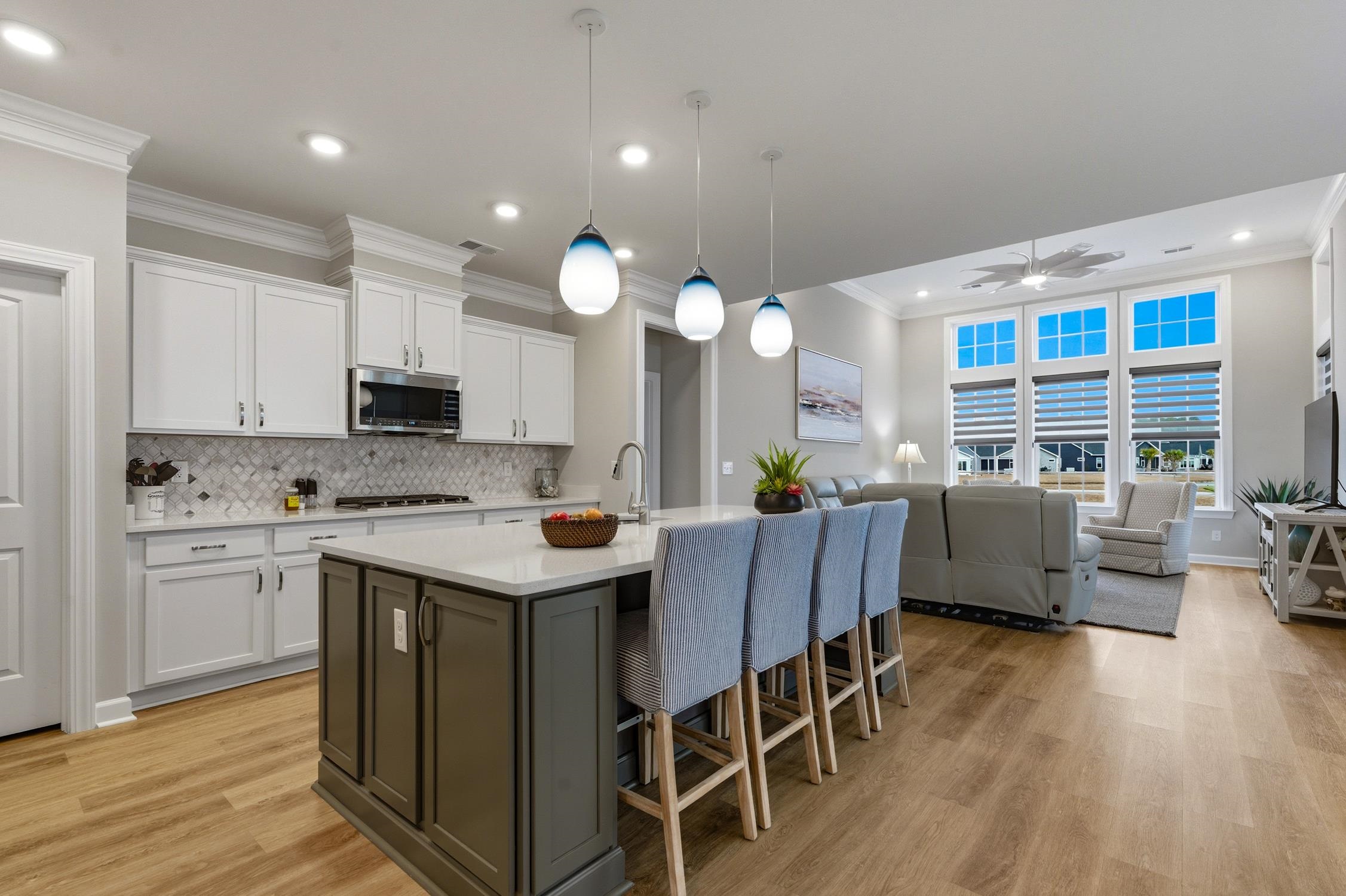 236 Bluestem Loop Little River, SC 29566 - Photo 40 of 40 Kitchen with white cabinetry, hanging light fixtures, crown molding, open floor plan, and a kitchen bar