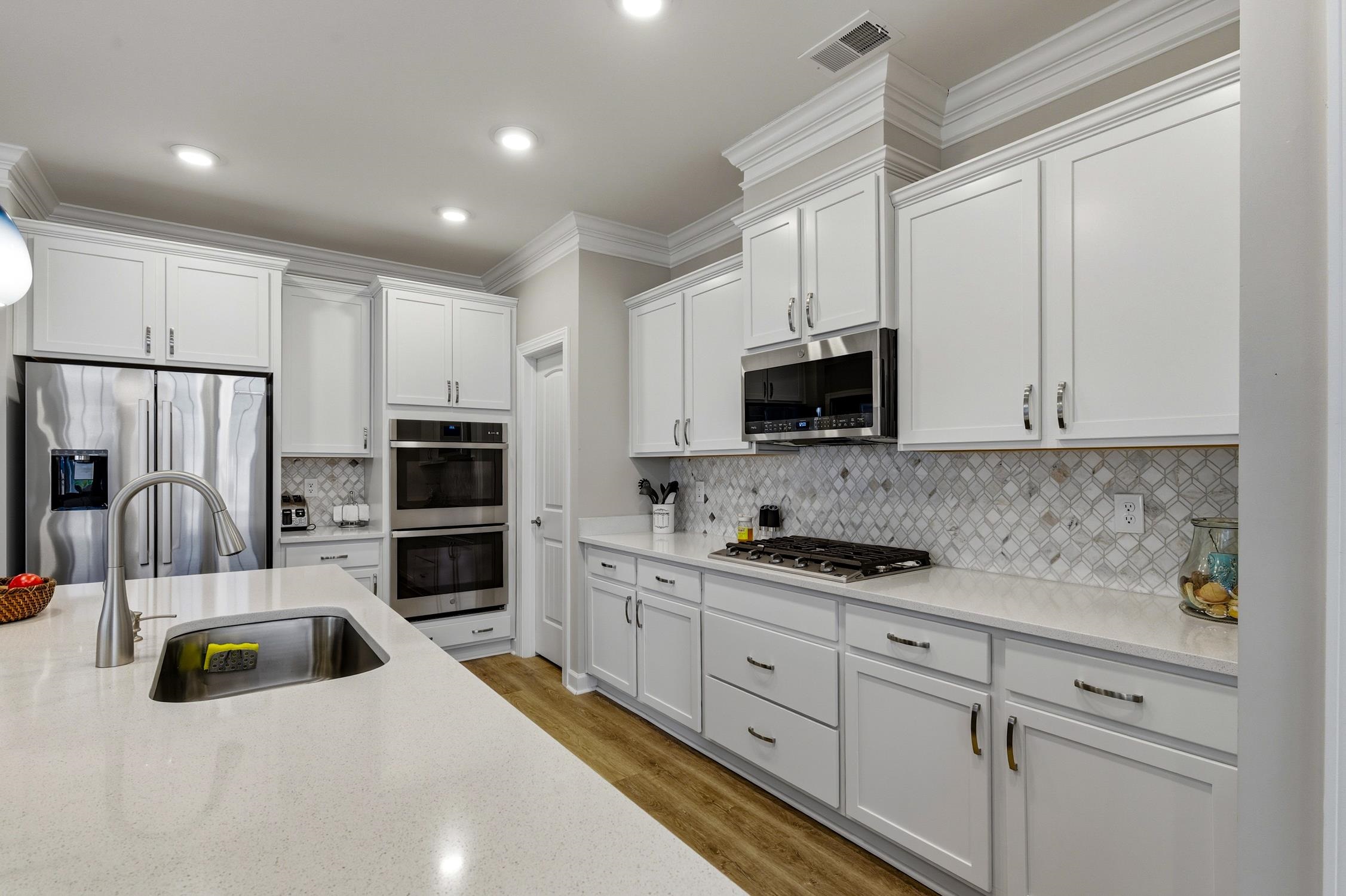 236 Bluestem Loop Little River, SC 29566 - Photo 9 of 40 Kitchen featuring stainless steel appliances, ornamental molding, white cabinets, light stone counters, and light wood-style floors