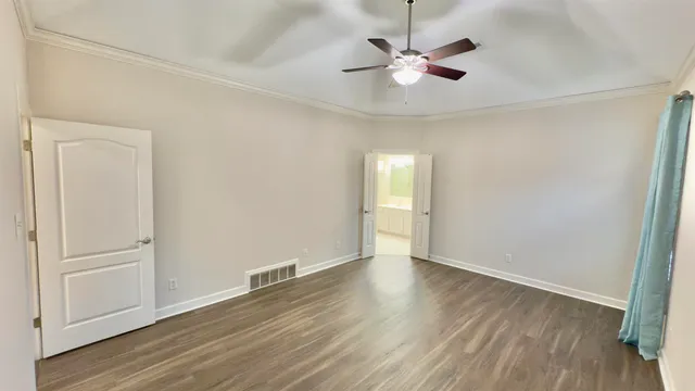 an empty room with wooden floor fan and windows