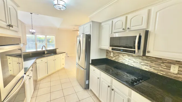 a open kitchen with granite countertop a stove a sink and a chandelier