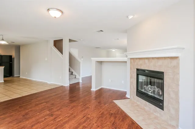 a view of an empty room with wooden floor fireplace and a window