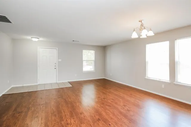 an empty room with wooden floor exposed radiator and windows