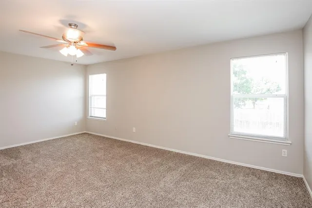 an empty room with windows and fan