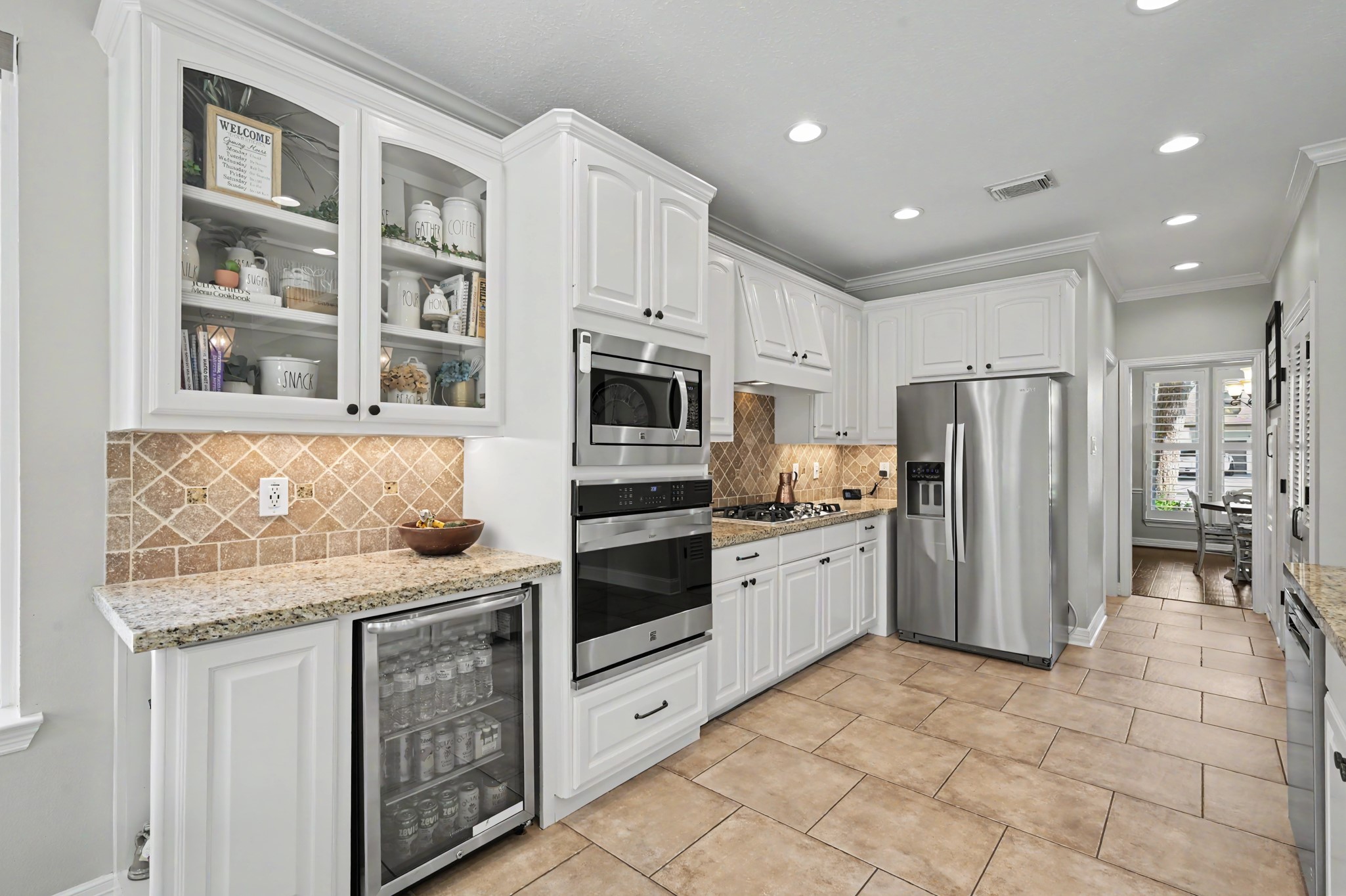 14938 Codys Run Cypress, TX 77429 - Photo 11 of 50 The kitchen features stainless appliances, including the built-in beverage refrigerator, glass front cabinets, and a built-in bookcase on the end of the cabinet. The recessed lighting and large windows make this workspace light and bright.