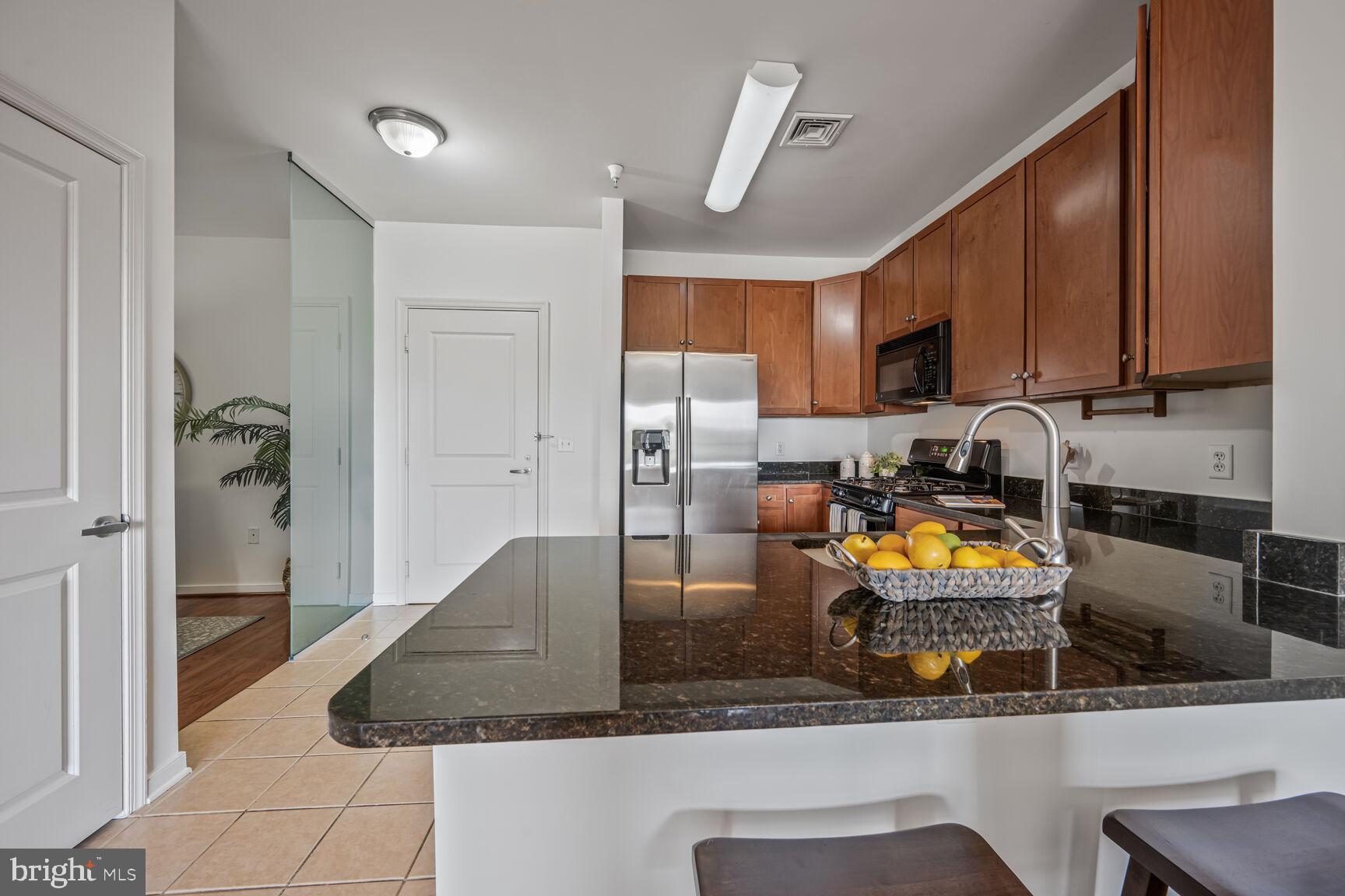 8045 Newell Street, Unit 516 Silver Spring, MD 20910 - Photo 13 of 33 a kitchen with a refrigerator a stove and a sink with wooden cabinets