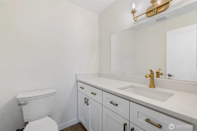 a bathroom with a granite countertop sink vanity mirror and toilet