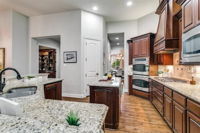 a kitchen with stainless steel appliances kitchen island granite countertop a sink stove and refrigerator