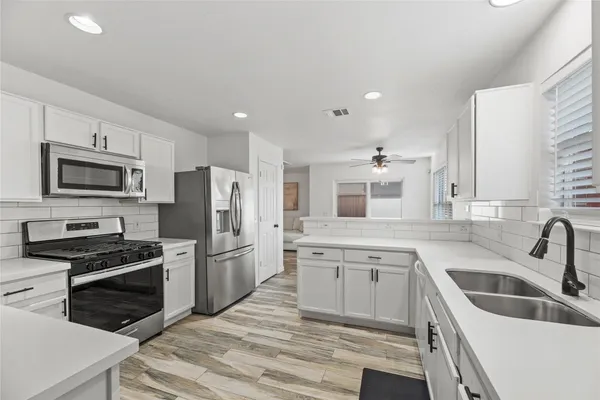 a kitchen with a sink stainless steel appliances and white cabinets