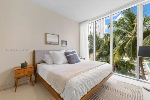 a bedroom with a bed and large windows