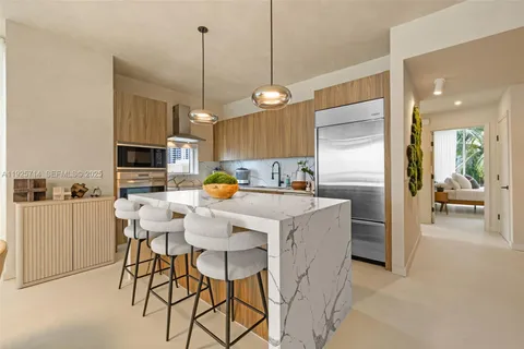 a kitchen with stainless steel appliances kitchen island granite countertop a refrigerator a stove a microwave oven a sink with a dining table and chairs