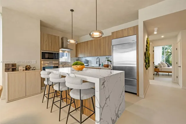 a kitchen with stainless steel appliances kitchen island granite countertop a refrigerator a stove a microwave oven a sink with a dining table and chairs