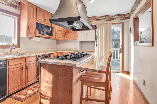 a kitchen with stainless steel appliances granite countertop a stove a sink dishwasher and cabinets with wooden floor
