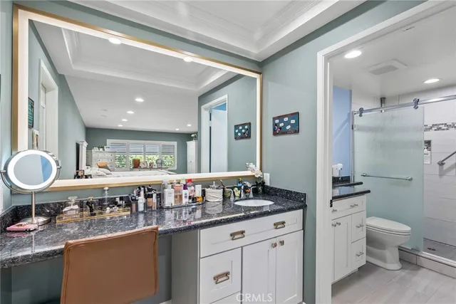 a spacious bathroom with a granite countertop sink a toilet a mirror and shower