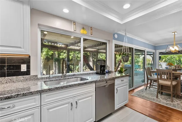 a open kitchen with granite countertop a sink and white cabinets next to a large window