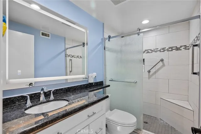 a bathroom with a granite countertop sink toilet and shower