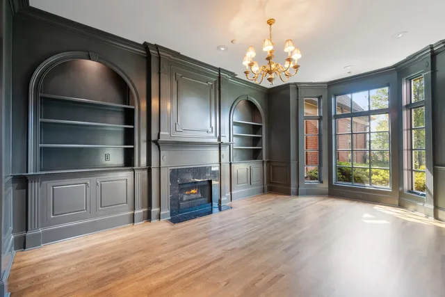a view of an empty room with wooden floor fireplace and a window