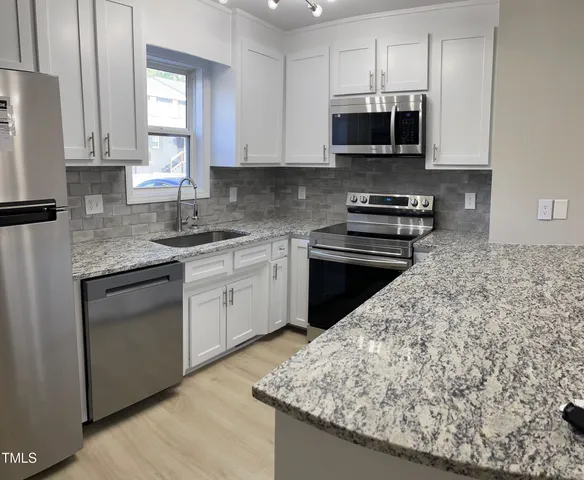 a kitchen with stainless steel appliances granite countertop a sink stove and microwave