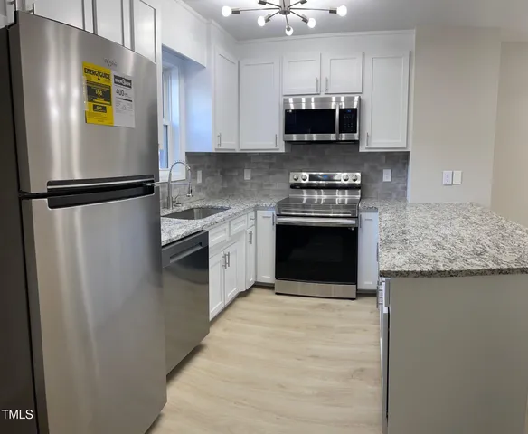 a kitchen with stainless steel appliances granite countertop a stove a refrigerator and a sink