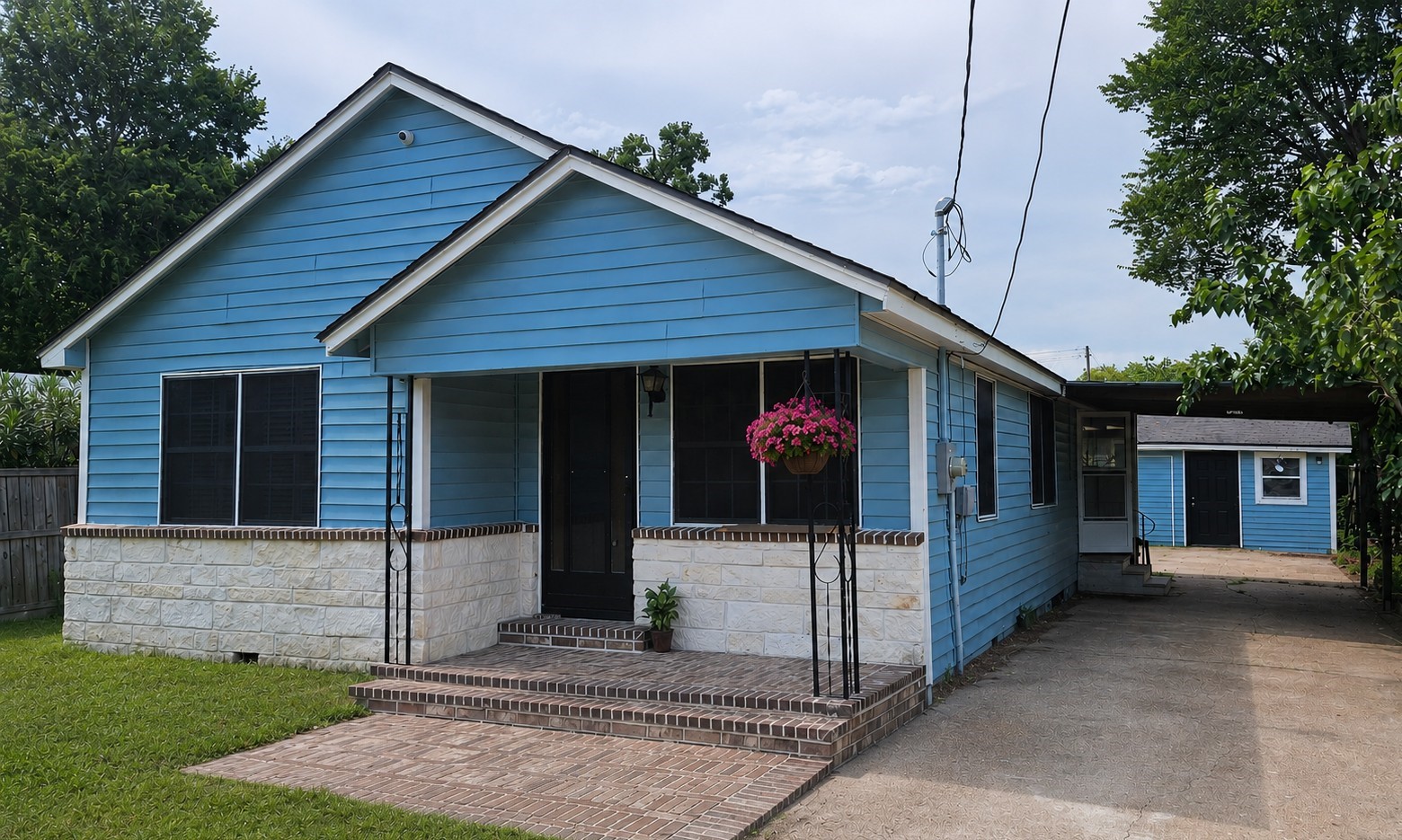2415 Perry Street Baytown, TX 77521 - Photo 1 of 23 Charming single-story blue house with a brick and stone facade. It features a welcoming front porch, a lush green lawn, and a driveway leading to a detached structure. Ideal for cozy living with additional space for storage or a workshop.