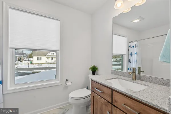 a bathroom with a granite countertop sink toilet and mirror