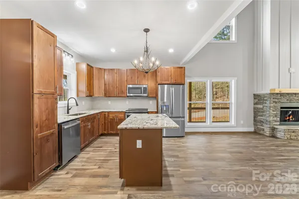 a kitchen with granite countertop a stove top oven a refrigerator a sink and dishwasher
