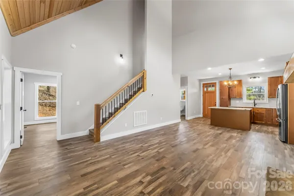 a view of a kitchen and an empty room with wooden floor