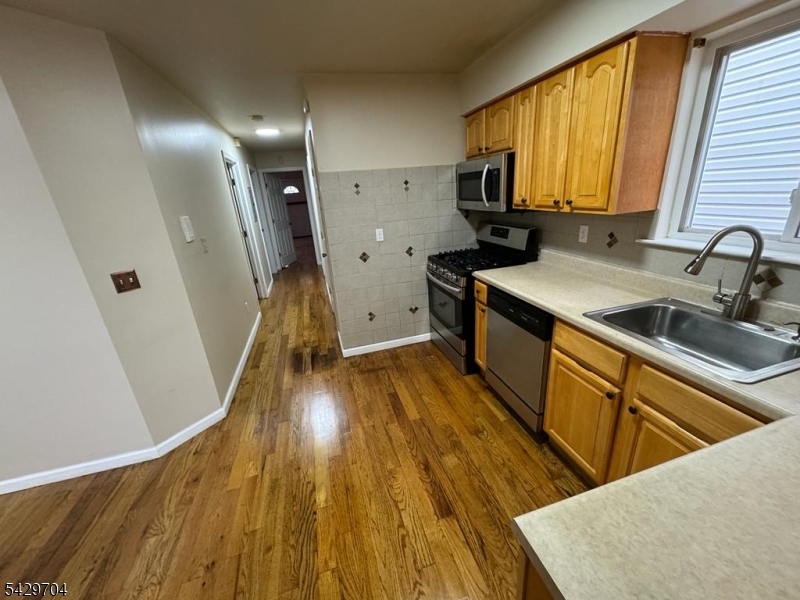 821 Anna Street Elizabeth, NJ 07201 - Photo 9 of 11 a kitchen with wooden floors a sink a stove and a microwave