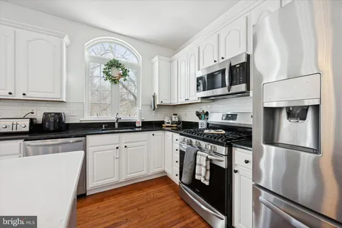 a kitchen with stainless steel appliances granite countertop a stove a sink and a refrigerator