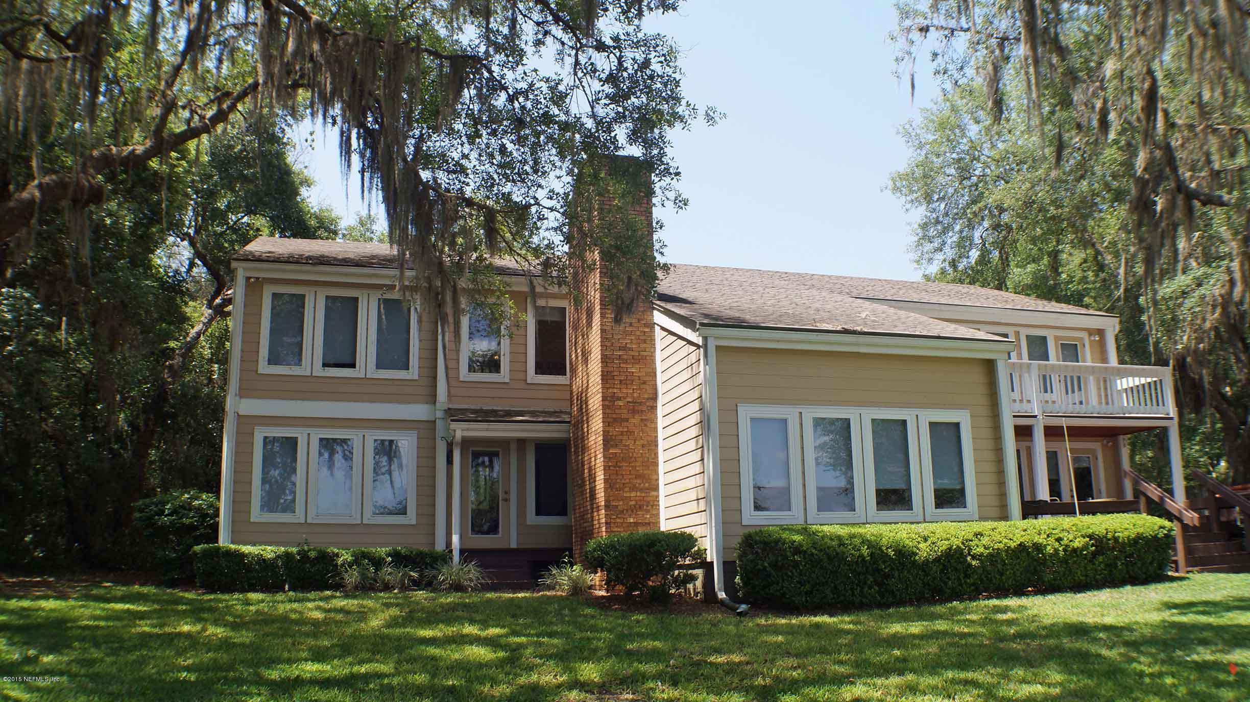6674 Brooklyn Bay Road Keystone Heights, FL 32656 - Photo 2 of 57 a view of a brick house with a large windows and a yard with plants and large trees