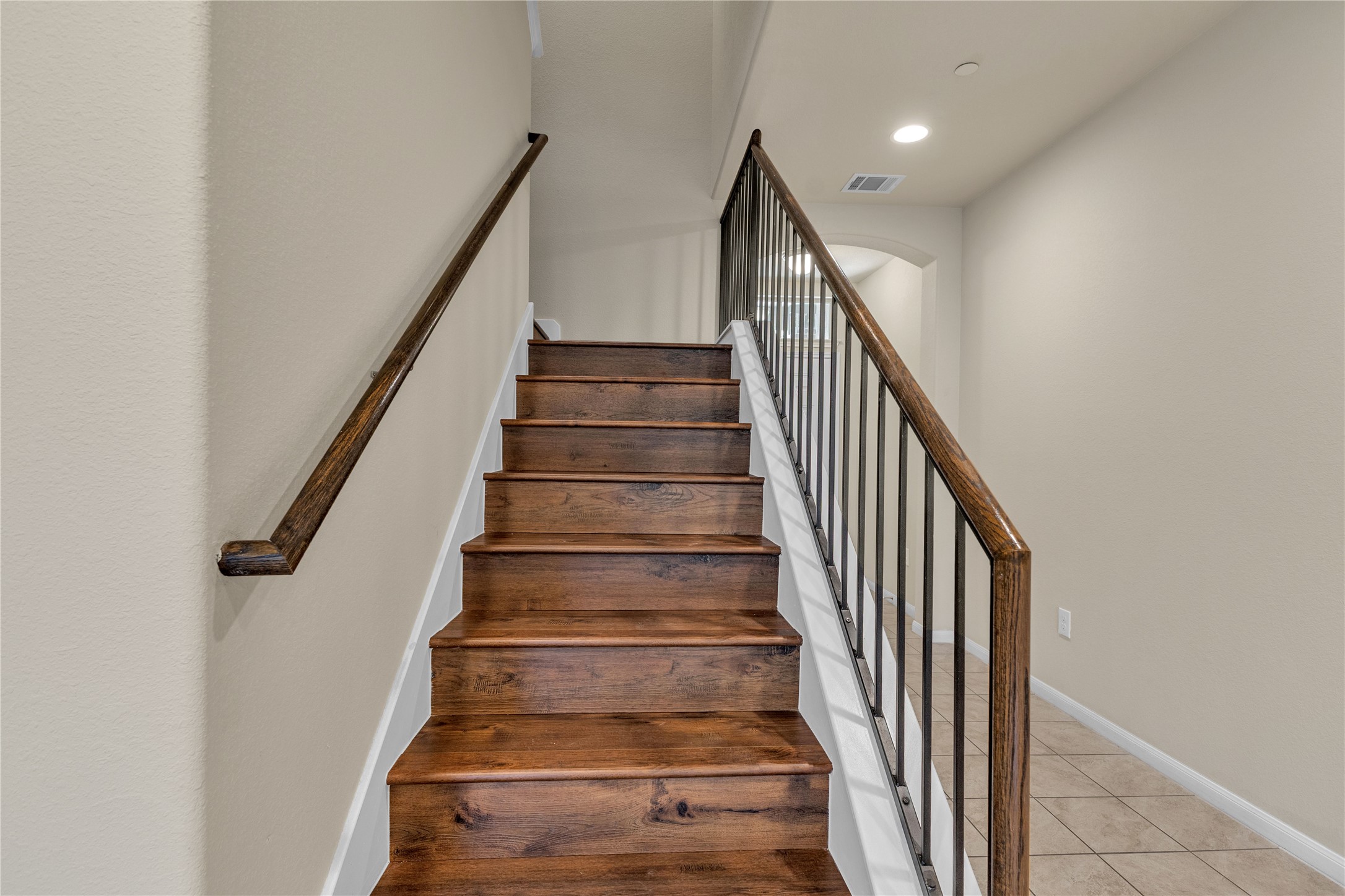 2880 Donnell Drive, Unit 2003 Round Rock, TX 78664 - Photo 17 of 31 Staircase featuring wood-finish treads and risers, a wood-finish handrail, and wrought iron balusters