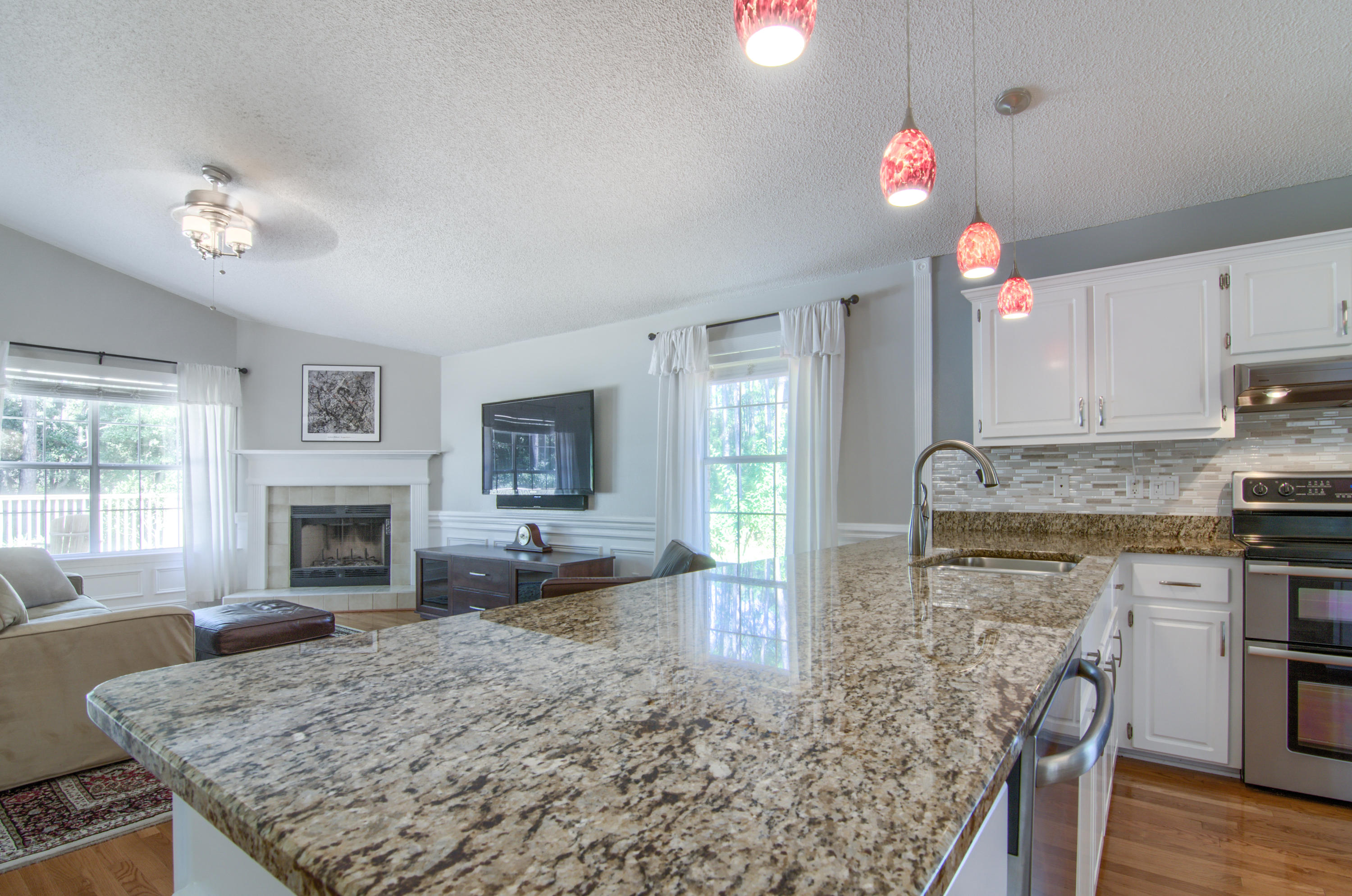 3840 Mesa Road Destin, FL 32541 - Photo 9 of 11 a kitchen with kitchen island granite countertop a stove top oven a sink a counter space and living room view