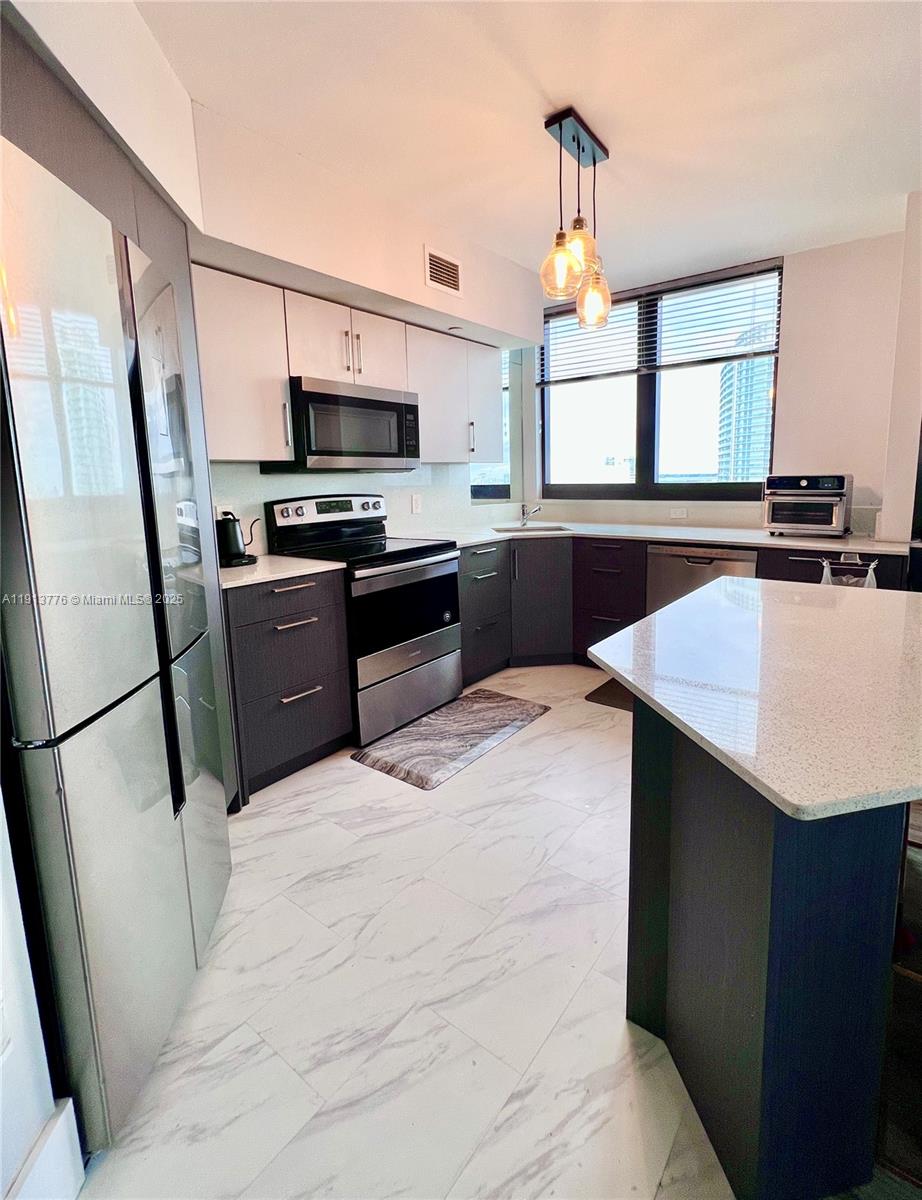 1330 West Avenue, Unit 1807 Miami Beach, FL 33139 - Photo 2 of 17 a kitchen with stainless steel appliances a refrigerator sink and stove
