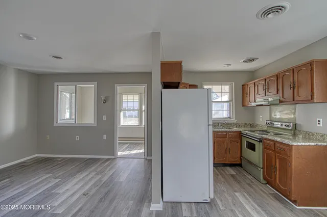 a kitchen with stainless steel appliances granite countertop a refrigerator a sink dishwasher a stove with wooden cabinets and floors