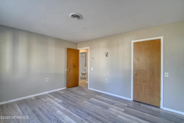 a view of an empty room with wooden floor and closet
